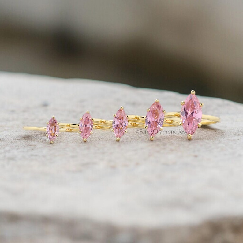 Puede incluir: Cinco anillos de oro con piedras preciosas de forma marquesa rosa. Los anillos est&aacute;n dispuestos en orden de tama&ntilde;o, con el anillo m&aacute;s grande a la izquierda y el m&aacute;s peque&ntilde;o a la derecha.