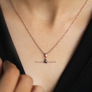 Puede incluir: Un delicado collar de cadena de oro rosa con un peque&ntilde;o colgante de l&aacute;grima negra. El colgante est&aacute; engastado con un solo diamante negro. "FancyDiamondsAndJewels" est&aacute; impreso debajo del colgante.