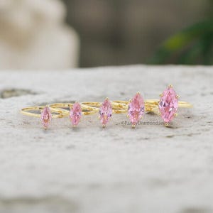 Puede incluir: Cinco anillos de oro con piedras preciosas de forma marquesa rosa. Los anillos est&aacute;n dispuestos en una fila del m&aacute;s peque&ntilde;o al m&aacute;s grande.