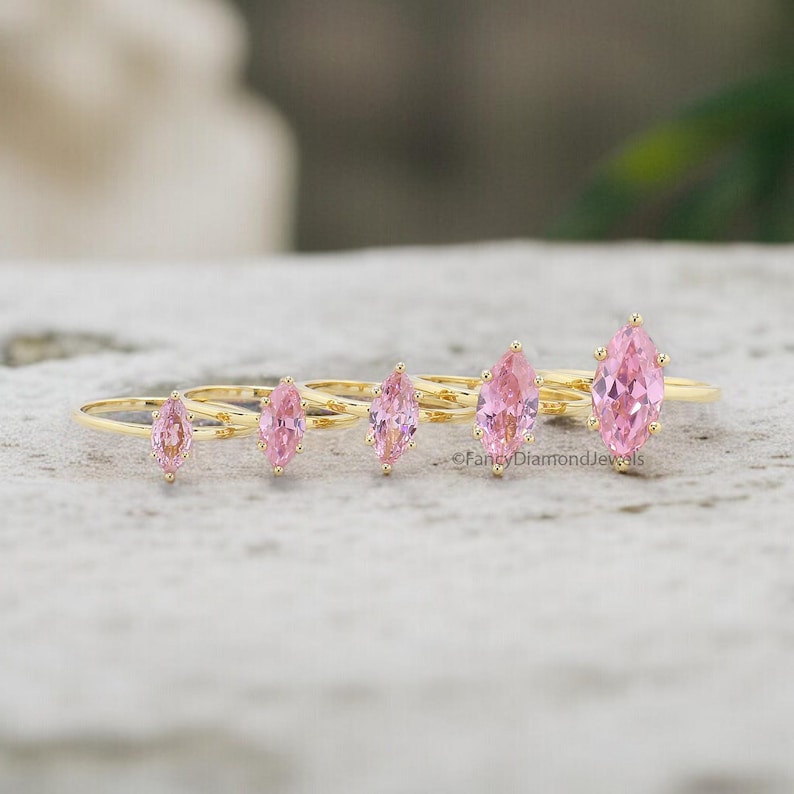 Puede incluir: Cinco anillos de oro con piedras preciosas de forma marquesa rosa. Los anillos est&aacute;n dispuestos en una fila del m&aacute;s peque&ntilde;o al m&aacute;s grande.