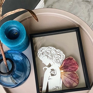 Papiergeschnittenes Mädchen „Fee“, handgeschnittene Papierkunst, originaler Papierschnitt in weißer Farbe mit getrockneten Tulpenblättern, Kunstglasrahmen, gerahmte Kunst