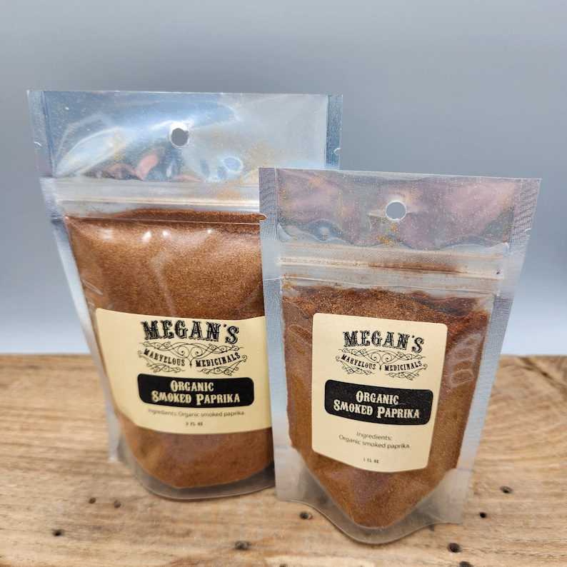 Two clear plastic bags filled with organic smoked paprika. The bags are labeled with the text "Megan's Marvelous Medicinals" and "Organic Smoked Paprika".