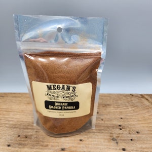 A clear plastic bag filled with a brown powder labeled "Megan's Marvelous & Medicinals Organic Smoked Paprika". The label also includes the ingredients: "Organic smoked paprika".