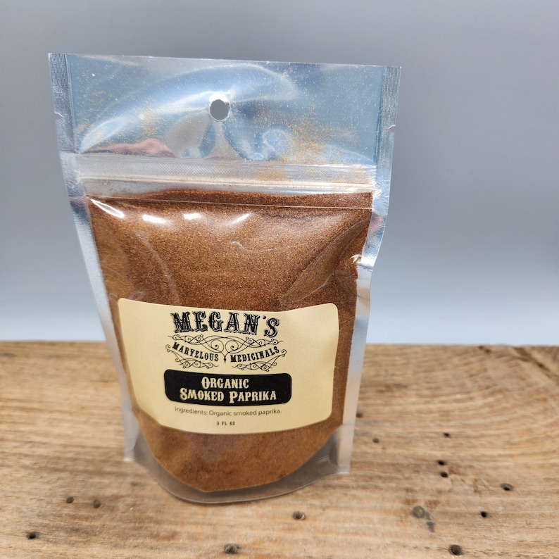 A clear plastic bag filled with a brown powder labeled "Megan's Marvelous & Medicinals Organic Smoked Paprika". The label also includes the ingredients: "Organic smoked paprika".