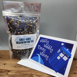 May include: A clear bag of Galli-Grey Regeneration Tea with blue and yellow tea leaves. A greeting card with a blue police box illustration and the words "Wibbly Wobbly Timey Wimey" is next to the tea.