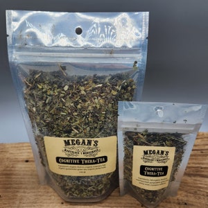 May include: Two clear plastic bags filled with loose leaf tea. The larger bag has a label that reads "Megan's Marvelous Medicinals Cognitive Thera-Tea" and lists the ingredients as "All organic: Brahmi, organic rosemary leaf, organic gunpowder green tea, organic yerba mate". The smaller bag has a label that reads "Megan's Marvelous Medicinals Cognitive Thera-Tea" and lists the ingredients as "All organic: Brahmi, rosemary leaf, organic gunpowder green tea, yerba mate. Contains caffeine."