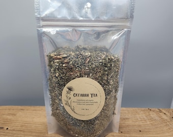 May include: A clear, resealable pouch filled with loose-leaf tea. A round label on the front reads "Catarrh Tea" with a botanical illustration and ingredient list. The tea blend appears to be a mix of dried herbs and leaves.