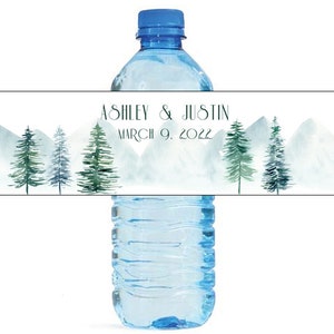 May include: Water bottle label with a watercolor design of mountains and pine trees. The label says "Ashley & Justin March 9, 2022".