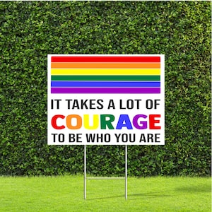 May include: A white yard sign with a rainbow pride flag and the text "It takes a lot of courage to be who you are."