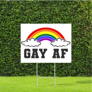 May include: A white yard sign with a rainbow and the text "GAY AF" in black letters.