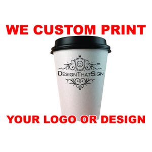 May include: A white paper coffee cup with a black lid. The cup features a black logo with the text "Design That Sign" and the words "WE CUSTOM PRINT YOUR LOGO OR DESIGN" in red.