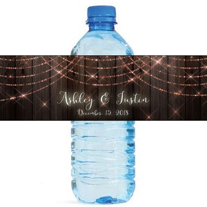 May include: Water bottle label with a rustic wood background and copper string lights. The label says "Ashley & Justin" and "December 15, 2018".