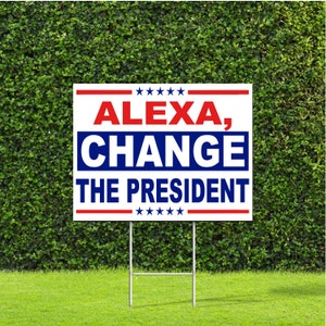 May include: A white yard sign with red and blue text that reads "ALEXA, CHANGE THE PRESIDENT" with stars above and below the text.