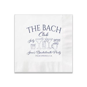 May include: White paper cocktail napkin with blue text that reads "The Bach Club July 2025 Jenn's Bachelorette Party Palm Springs, CA".  The napkin features a line of six different cocktail drawings.