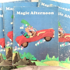 May include: A stack of vintage children's books titled "Magic Afternoon." The cover art features a red car with whimsical characters, including a rabbit and a mouse, against a blue sky with star accents. The books have a worn, aged appearance.