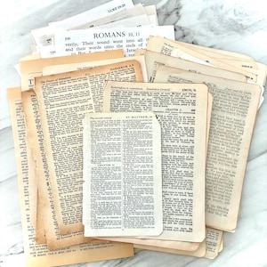 May include: A collection of aged book pages with text from the Bible. The pages vary in size and shape, with visible text from Romans, Habakkuk, and Matthew. The paper has a yellowed, vintage appearance.