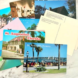 May include: A collection of vintage postcards featuring scenes from St. Augustine, Florida. The postcards showcase historical buildings, horse-drawn carriages, and palm trees, with text that reads "St. Augustine, Florida."
