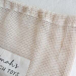 May include: A beige mesh bag with a white fabric patch that says "Tomah's Beach Toys".