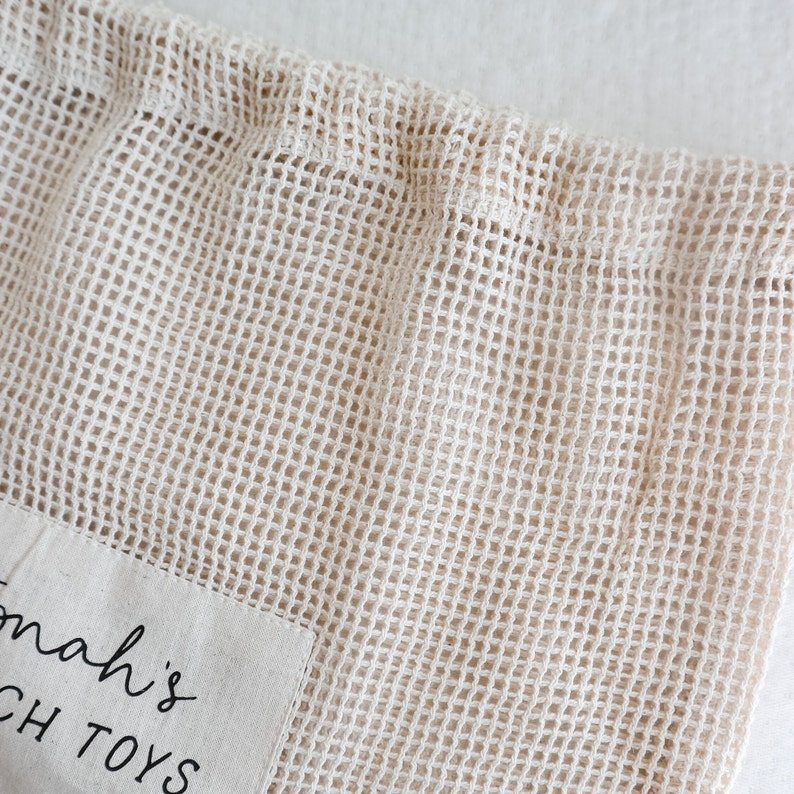 May include: A beige mesh bag with a white fabric patch that says "Tomah's Beach Toys".