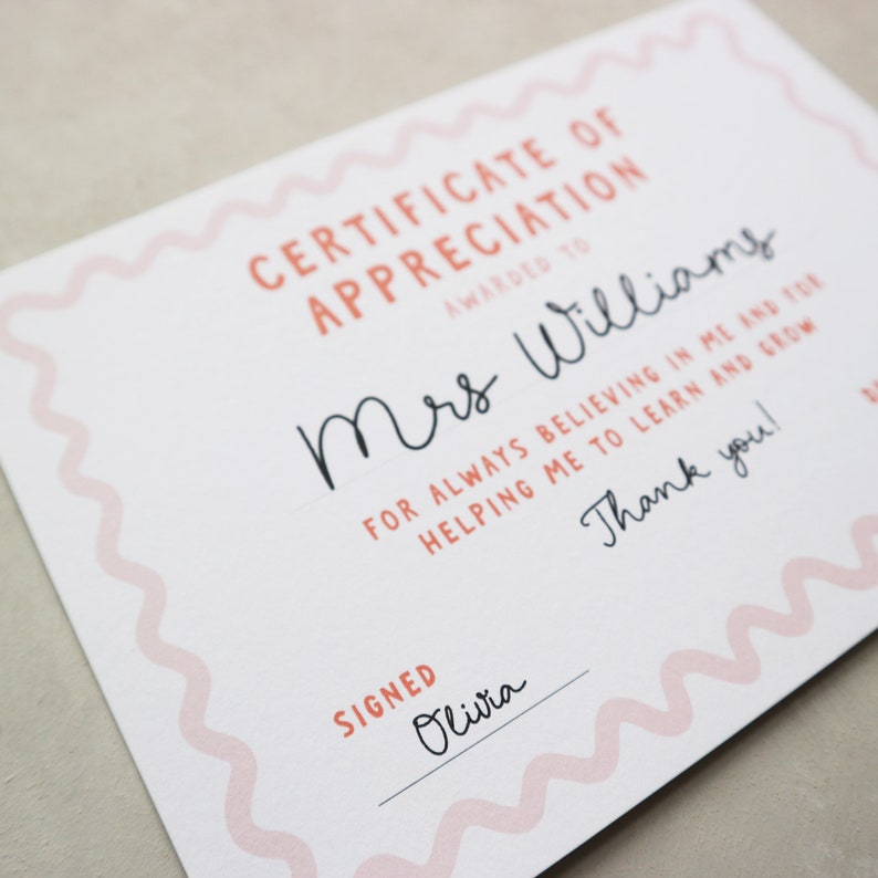May include: A white certificate of appreciation with pink wavy borders. The text reads "Certificate of Appreciation Awarded to Mrs. Williams for always believing in me and for helping me to learn and grow. Thank you! Signed Olivia."