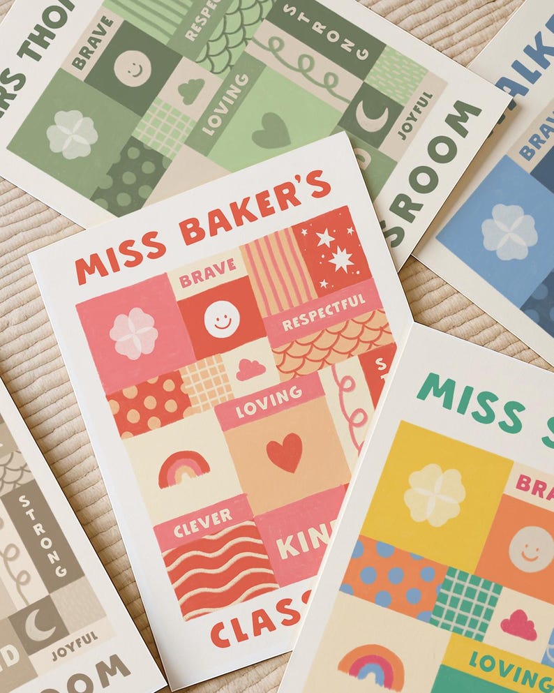 May include: A collection of rectangular art prints featuring a grid of squares with various patterns and words including "MISS BAKER'S", "BRAVE", "RESPECTFUL", "LOVING", "CLEVER", and "KIN". The designs incorporate icons like hearts, rainbows, stars, and smiley faces in red, pink, orange, yellow, green, and blue color palettes.