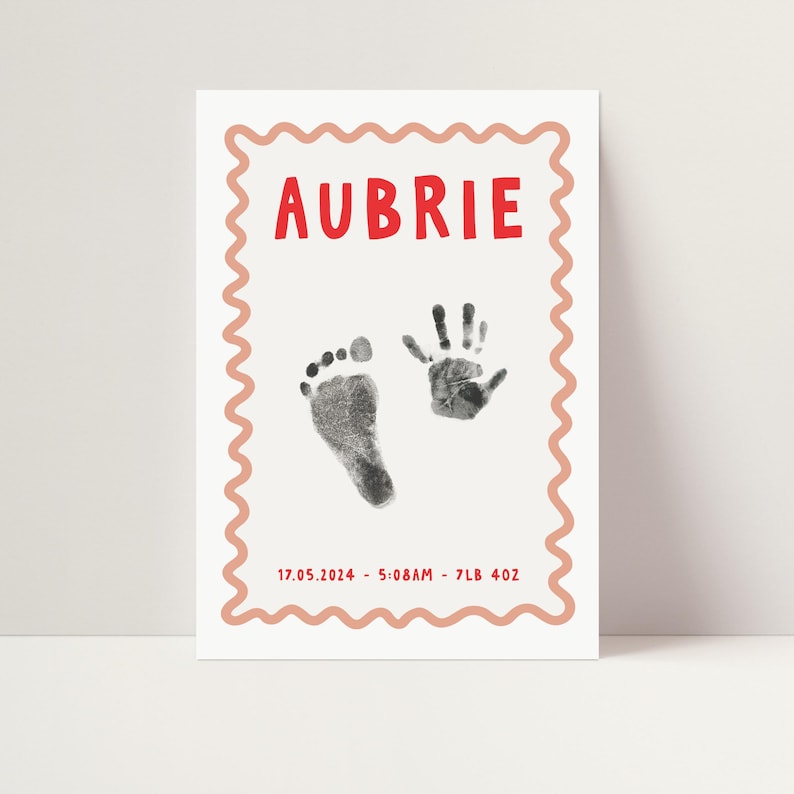 Pu&ograve; includere: Un biglietto bianco con un bordo rosa a festoni. Il nome "AUBRIE" &egrave; stampato in lettere rosse. Ci sono impronte di mani e piedi nere sul biglietto. La data "17.05.2024", l'ora "5:08AM", il peso "7LB 4OZ" sono stampati in nero sotto le impronte.