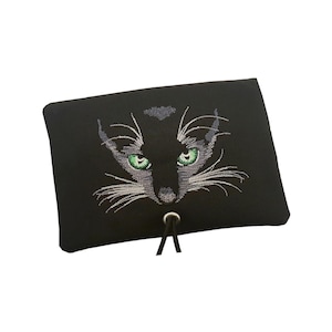 Puede incluir: Un estuche rectangular negro con un diseño bordado de una cara de gato con ojos de color verde brillante y largos bigotes blancos. El estuche incluye un ojal metálico plateado en el centro con dos cordones negros que cuelgan hacia abajo.