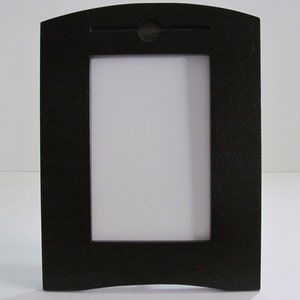 May include: A black wooden picture frame with a curved top and bottom. The frame has a simple design and is ready to display a photo or artwork.