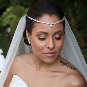 May include: A bride wearing a white veil and a beaded headpiece. She is looking down and has a tattoo on her shoulder that says "Vita e Bella".