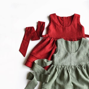 May include: Two linen dresses with matching sashes. The top dress is red and the bottom dress is green.