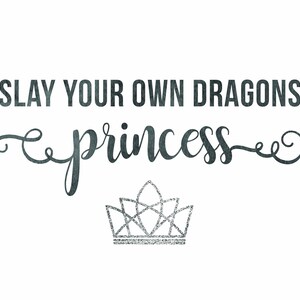 May include: A black and white graphic with the text "SLAY YOUR OWN DRAGONS princess" in a cursive font. A silver glitter crown is below the text.