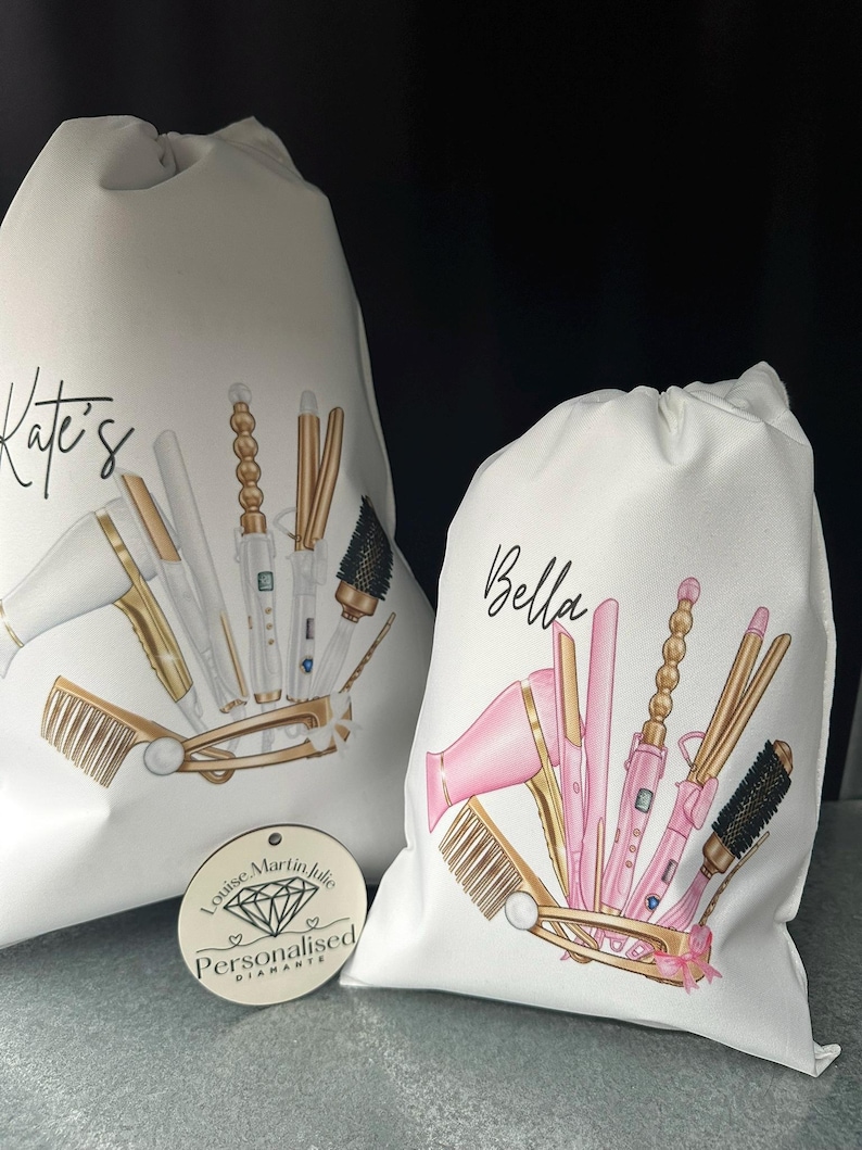 Pode incluir: Duas bolsas de lona brancas com cord&atilde;o de ajuste, personalizadas com os nomes "Kate's" e "Bella". Cada bolsa apresenta uma ilustra&ccedil;&atilde;o colorida de ferramentas para pentear o cabelo, incluindo um secador de cabelo, um modelador de cachos, uma prancha e escovas. As bolsas s&atilde;o perfeitas para guardar e organizar as ferramentas para pentear o cabelo.
