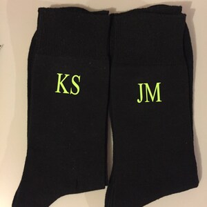 May include: Two pairs of black socks with the initials "KS" and "JM" embroidered in green on the front.