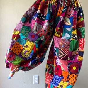 May include: Colorful patchwork pants with a high waist and wide legs. The pants are made of a variety of fabrics in different colors and patterns, including red, yellow, green, blue, and purple.