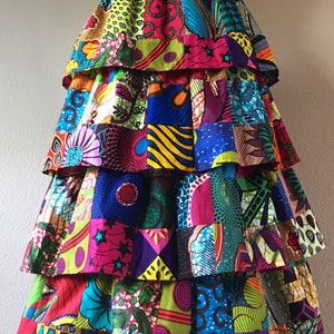 Könnte beinhalten: Ein mehrschichtiger Rock aus buntem Patchwork-Stoff. Der Rock weist eine Vielzahl von leuchtenden Mustern und Farben auf, darunter Rosa, Blau, Grün und Gelb. Der Rock wird auf einer Schaufensterpuppe präsentiert.