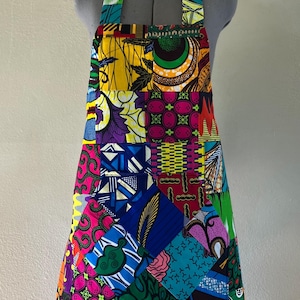 May include: A colourful patchwork apron featuring a range of bright colours and patterns, including yellow, green, blue, pink and red.