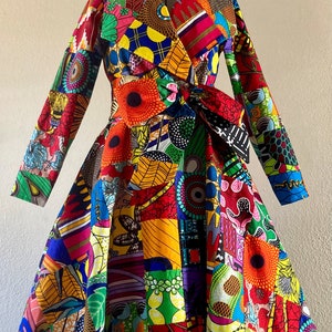 May include: A vibrant, patchwork-style wrap dress with long sleeves. The dress features a colorful mix of geometric and floral patterns in red, yellow, blue, and green. It has a waist tie and a flared skirt, showcasing a bold and artistic design.