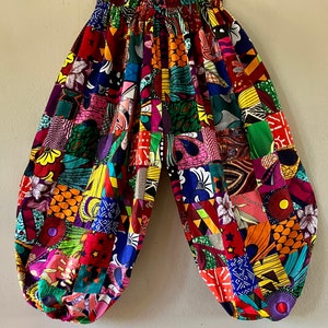 Puede incluir: Pantalones de patchwork coloridos con una cintura el&aacute;stica de talle alto. Los pantalones est&aacute;n hechos de una variedad de telas en colores brillantes, incluyendo rojo, verde, amarillo, azul y morado.