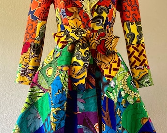 May include: A vibrant, patchwork-style dress with a blazer-like top. The dress features a V-neck, long sleeves, and a belted waist. The fabric is a mix of colorful patterns in shades of red, orange, yellow, green, blue, and purple.
