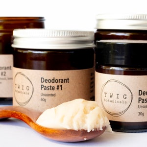May include: Several brown glass jars with metal lids, labelled "Deodorant Paste #1" and "Deodorant Paste #2" from Twig Botanicals. A wooden spoon displays a sample of the unscented paste. The jars have tan labels.
