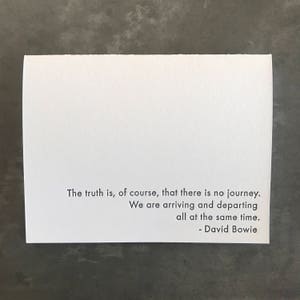May include: A white card with a black quote by David Bowie that reads: "The truth is, of course, that there is no journey. We are arriving and departing all at the same time."