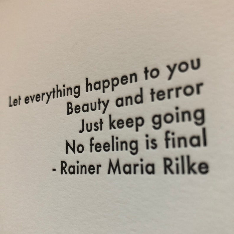 Puede incluir: Texto en blanco y negro sobre un fondo blanco. El texto dice: "Deja que todo te suceda Belleza y terror Sigue adelante Ning&uacute;n sentimiento es final - Rainer Maria Rilke"