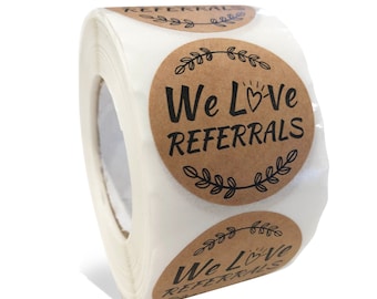 Może przedstawiać: Rolkę brązowych naklejek z papieru kraft z tekstem "We Love Referrals" czarnymi literami z symbolem serca. Naklejki mają czarny kwiatowy wzór wokół krawędzi.