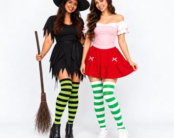 May include: Two costumes: one black dress with a witch hat and black boots, paired with black and green striped stockings and a broom. The other is a pink and white off-the-shoulder top with a red skirt, white and green striped stockings, and white sneakers.