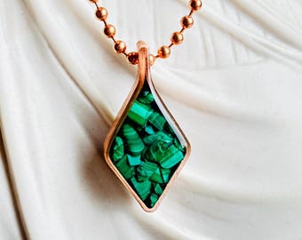May include: A copper necklace with a diamond-shaped pendant featuring a green malachite stone.