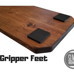 K&ouml;nnte beinhalten: Nahaufnahme einer Holzplatte mit zwei schwarzen Anti-Rutsch-F&uuml;&szlig;en an der Unterseite. Der Text "Gripper Feet" ist unter der Platte gedruckt. Das Logo "SLIVER WOODWORKING" ist in einem Kreis unter dem Text gedruckt.