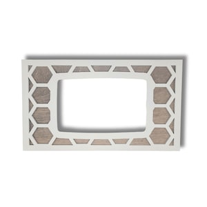 May include: A rectangular white wooden frame with a geometric honeycomb design. The frame has a light brown wood backing and a rectangular opening in the center.