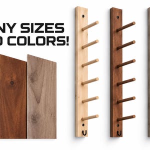 May include: Three vertical wooden wall racks with six pegs each, displayed in light, medium, and dark wood tones. The text MANY SIZES AND COLORS! appears above three flat wooden boards showing the same light, medium, and dark wood finishes.
