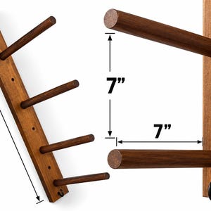 May include: A dark brown wooden wall rack featuring four horizontal pegs and a small metal hook at the bottom. The rack measures 15 inches in length, with 7 inches of vertical space between pegs and 7 inches of depth for each peg.