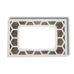May include: A rectangular white wooden picture frame with a geometric honeycomb design. The frame has a dark brown wood backing and a white border. The frame is designed to hold a rectangular photo.
